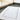 Plush white bath mat with a bordered design placed on a dark tiled bathroom floor near a glass shower.